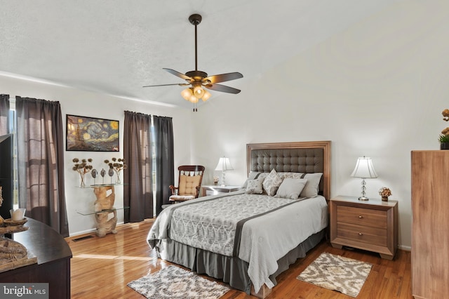 bedroom featuring ceiling fan, light hardwood / wood-style floors, and a textured ceiling