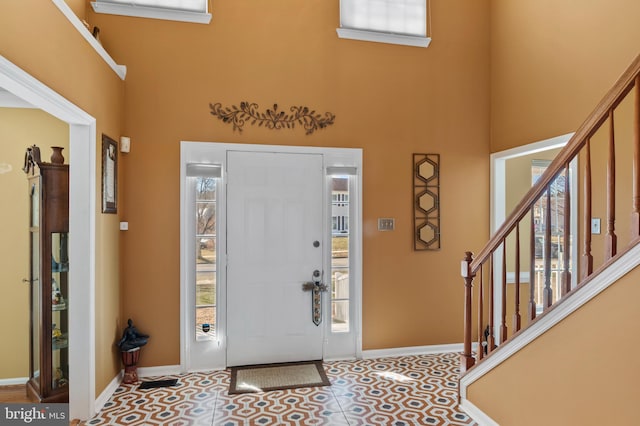 entrance foyer with a high ceiling, plenty of natural light, and tile patterned flooring