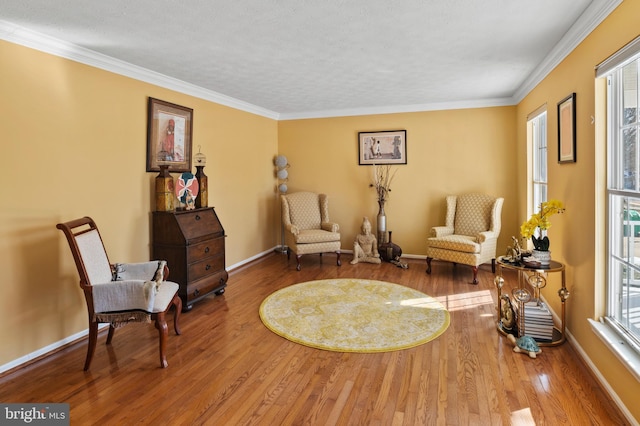 living area with hardwood / wood-style flooring, plenty of natural light, and crown molding