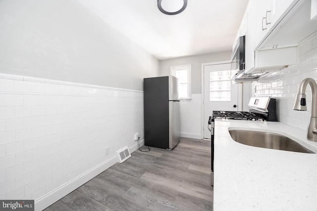 kitchen with sink, stainless steel appliances, white cabinets, and light stone countertops