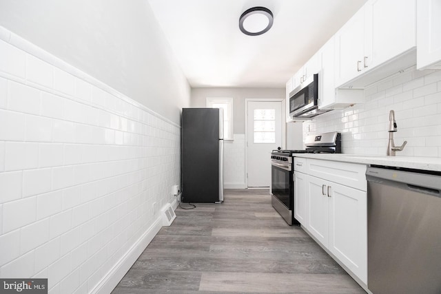 kitchen with white cabinetry, appliances with stainless steel finishes, sink, and light hardwood / wood-style floors