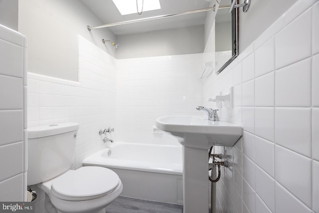 bathroom featuring wood-type flooring, toilet, shower / bath combination, and tile walls