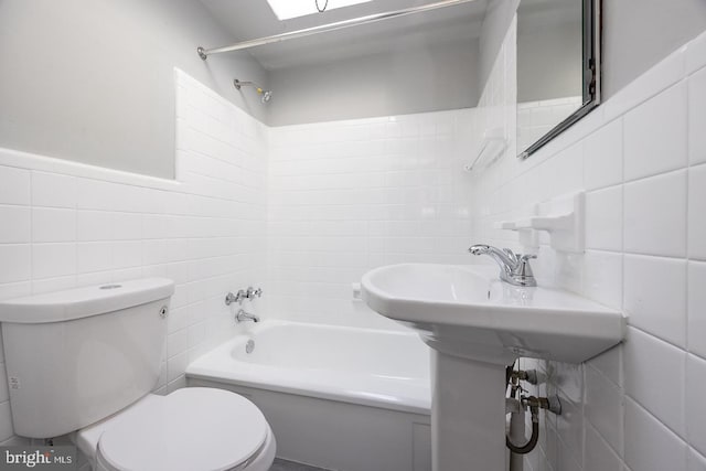 bathroom with toilet, tub / shower combination, and tile walls