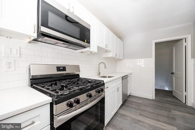 kitchen with sink, light stone counters, appliances with stainless steel finishes, hardwood / wood-style floors, and white cabinets