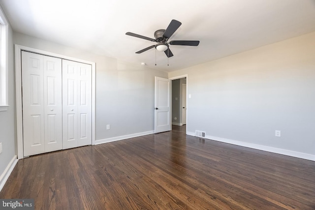 unfurnished bedroom with dark wood-type flooring, ceiling fan, and a closet