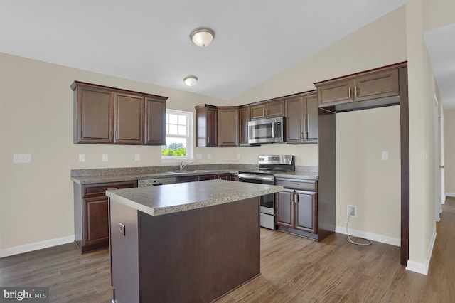 kitchen featuring lofted ceiling, appliances with stainless steel finishes, a kitchen island, and light hardwood / wood-style flooring