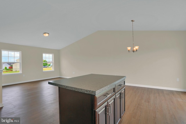 kitchen with lofted ceiling, hanging light fixtures, hardwood / wood-style floors, a center island, and dark brown cabinetry