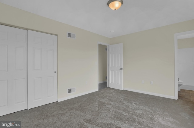 unfurnished bedroom featuring ensuite bathroom, carpet flooring, and a closet