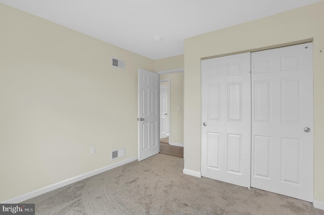 unfurnished bedroom featuring light colored carpet and a closet