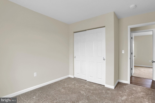 unfurnished bedroom with dark carpet and a closet