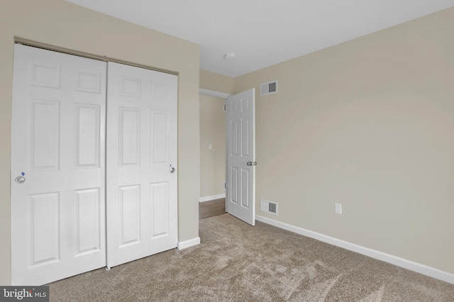 unfurnished bedroom with light colored carpet and a closet