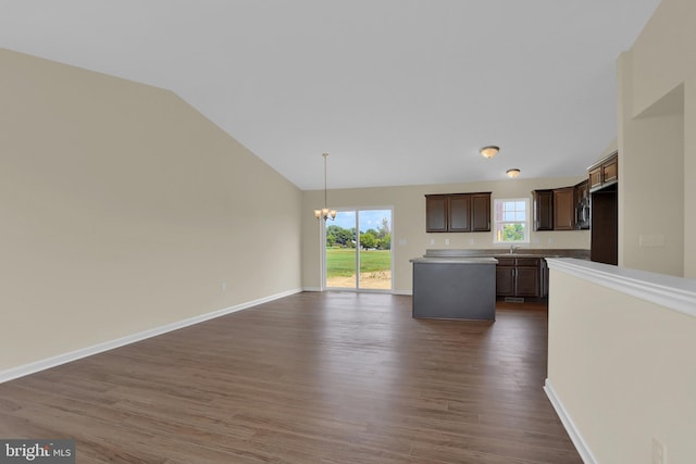 unfurnished living room with vaulted ceiling, dark hardwood / wood-style flooring, sink, and a chandelier