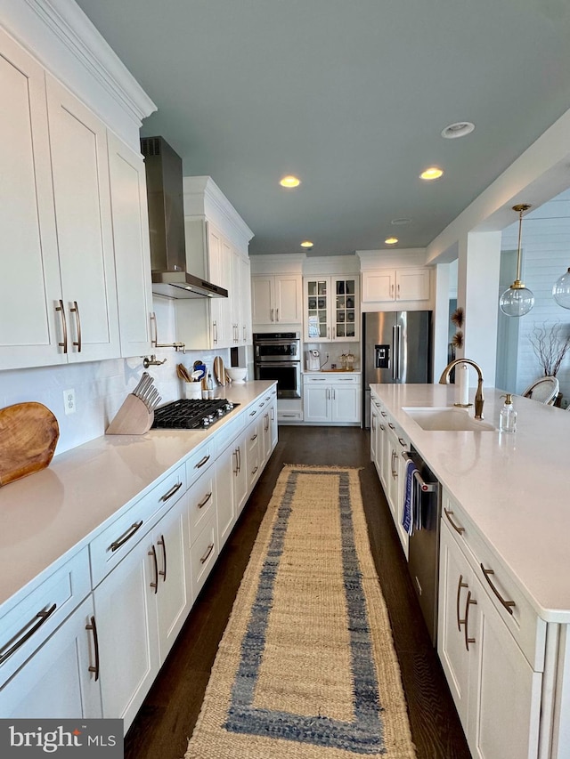 kitchen featuring white cabinetry, wall chimney exhaust hood, stainless steel appliances, and hanging light fixtures