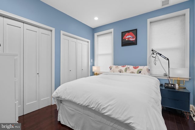 bedroom featuring dark hardwood / wood-style flooring and multiple closets