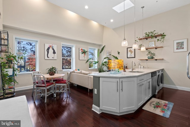 kitchen featuring pendant lighting, sink, a skylight, white cabinets, and kitchen peninsula