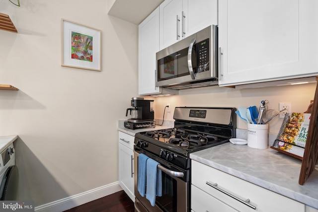 kitchen featuring washer / dryer, white cabinetry, appliances with stainless steel finishes, and dark hardwood / wood-style floors