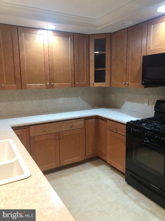 kitchen featuring tasteful backsplash, ornamental molding, sink, and black appliances