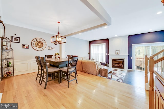 dining area with a large fireplace, a chandelier, and light hardwood / wood-style floors