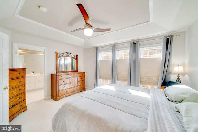 carpeted bedroom featuring ceiling fan, a raised ceiling, and ensuite bath