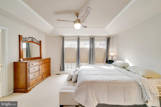 carpeted bedroom with ornamental molding, a raised ceiling, and ceiling fan