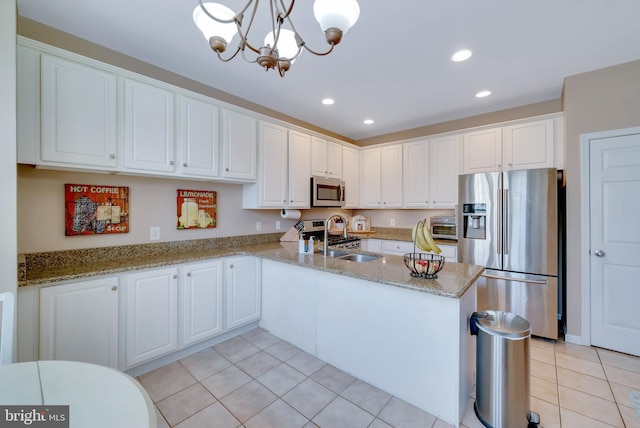 kitchen featuring appliances with stainless steel finishes, sink, white cabinets, hanging light fixtures, and kitchen peninsula