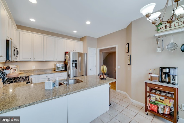 kitchen featuring light stone countertops, stainless steel appliances, kitchen peninsula, and white cabinets