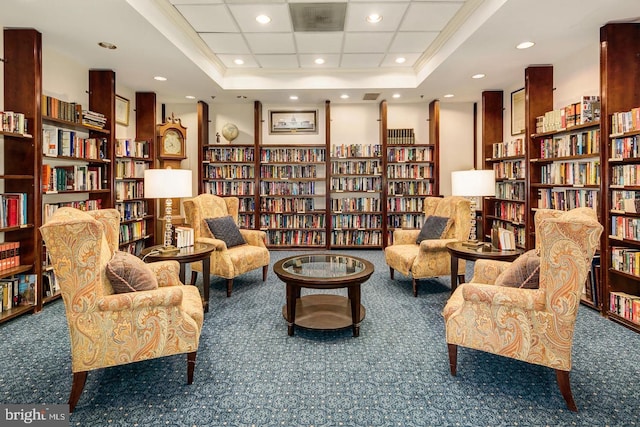 sitting room featuring crown molding, a tray ceiling, and dark colored carpet