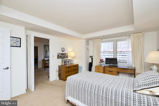 bedroom with a raised ceiling and light colored carpet