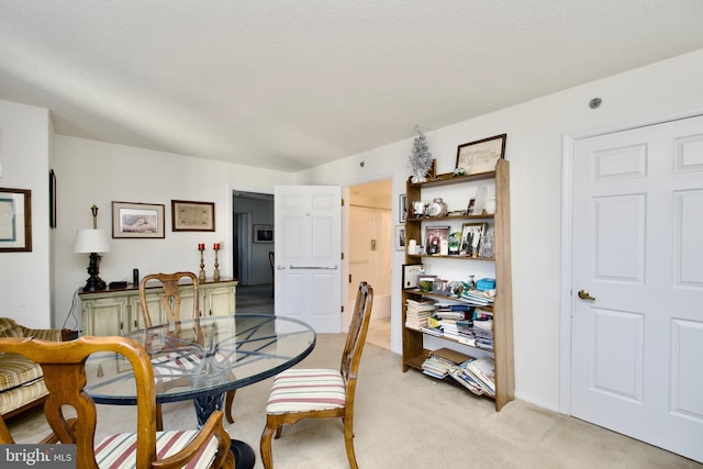 carpeted dining room with a textured ceiling