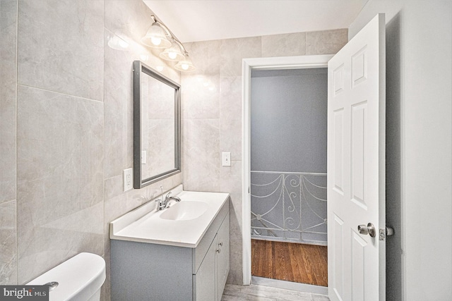 bathroom featuring vanity, toilet, hardwood / wood-style floors, and tile walls