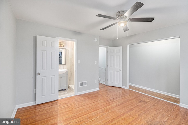 unfurnished bedroom with sink, light hardwood / wood-style flooring, ceiling fan, ensuite bath, and a closet