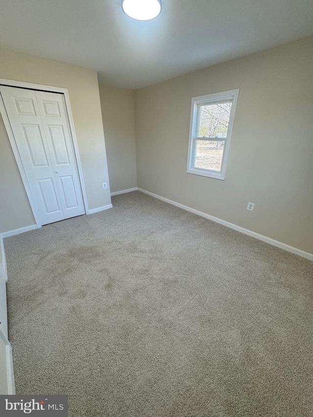 unfurnished bedroom with light colored carpet and a closet