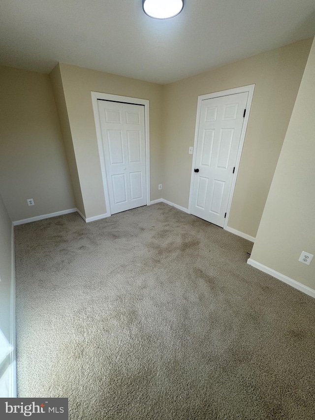 unfurnished bedroom featuring light carpet and a closet