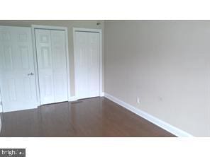 unfurnished bedroom featuring multiple closets and dark hardwood / wood-style flooring