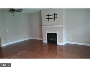 unfurnished living room with dark hardwood / wood-style floors and ceiling fan