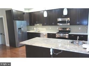 kitchen with dark brown cabinetry, appliances with stainless steel finishes, decorative light fixtures, and sink