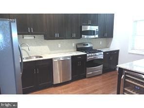 kitchen featuring stainless steel appliances, tasteful backsplash, sink, and dark wood-type flooring