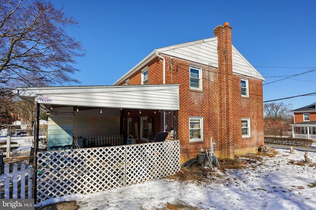 snow covered back of property featuring a porch