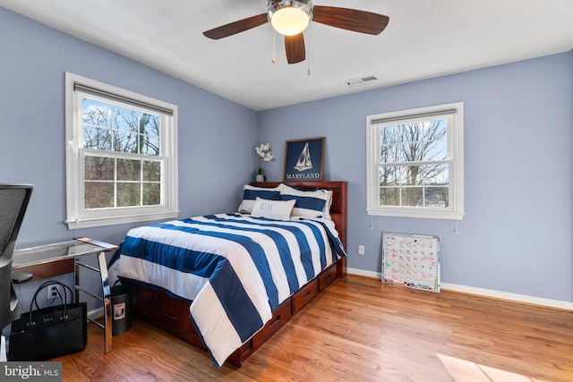 bedroom with ceiling fan, light hardwood / wood-style floors, and multiple windows