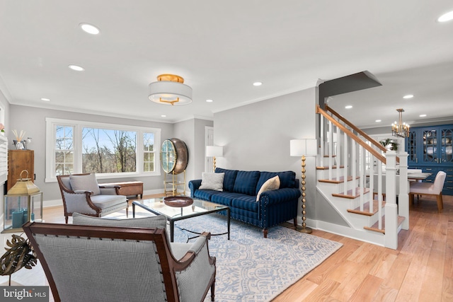 living room with ornamental molding, a notable chandelier, and light wood-type flooring