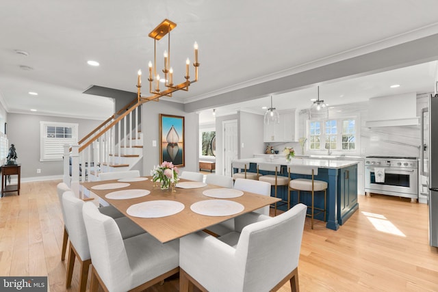 dining room featuring an inviting chandelier, sink, crown molding, and light wood-type flooring