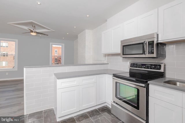 kitchen with white cabinetry, stainless steel appliances, and kitchen peninsula