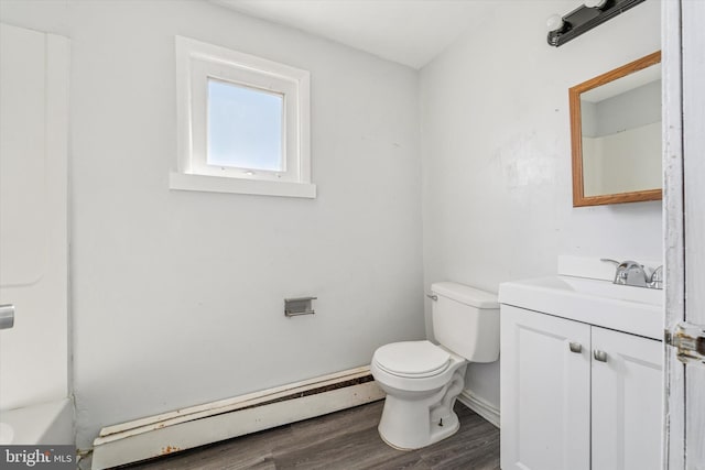 bathroom with toilet, wood finished floors, a baseboard radiator, a bathtub, and vanity