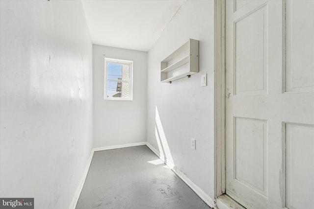 hallway featuring baseboards and concrete flooring