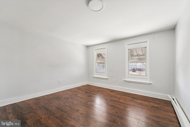 unfurnished room featuring a baseboard heating unit, baseboards, and hardwood / wood-style flooring