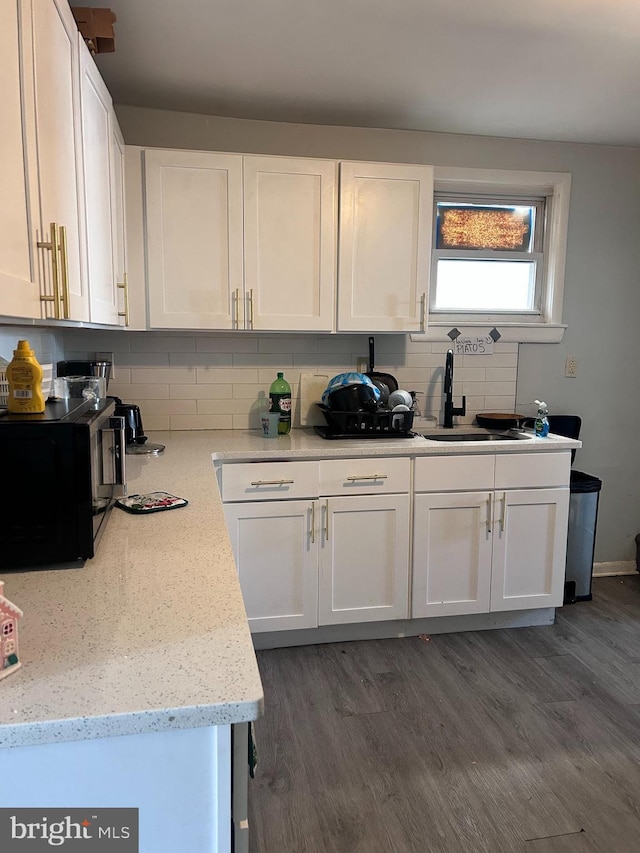 kitchen with white cabinetry, sink, backsplash, and light stone counters