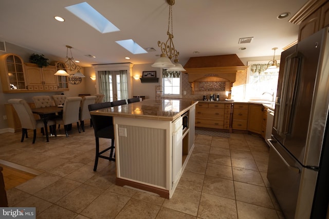 kitchen featuring premium range hood, a kitchen bar, a kitchen island, stainless steel appliances, and backsplash