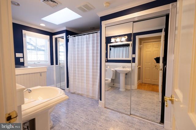 bathroom with curtained shower, a skylight, sink, ornamental molding, and toilet