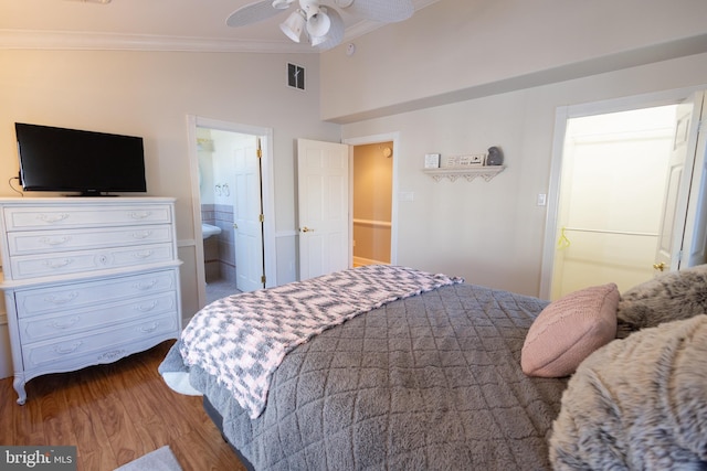 bedroom with crown molding, lofted ceiling, wood-type flooring, and ensuite bath