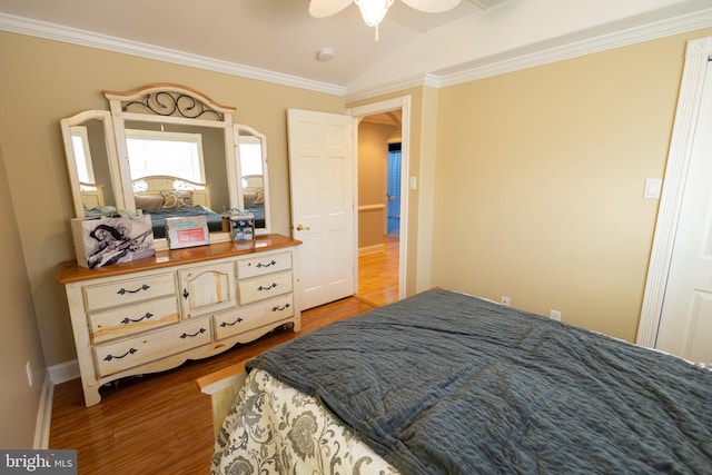 bedroom featuring ceiling fan, ornamental molding, lofted ceiling, and light hardwood / wood-style flooring